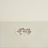 Small round plate with floral design on a beige background