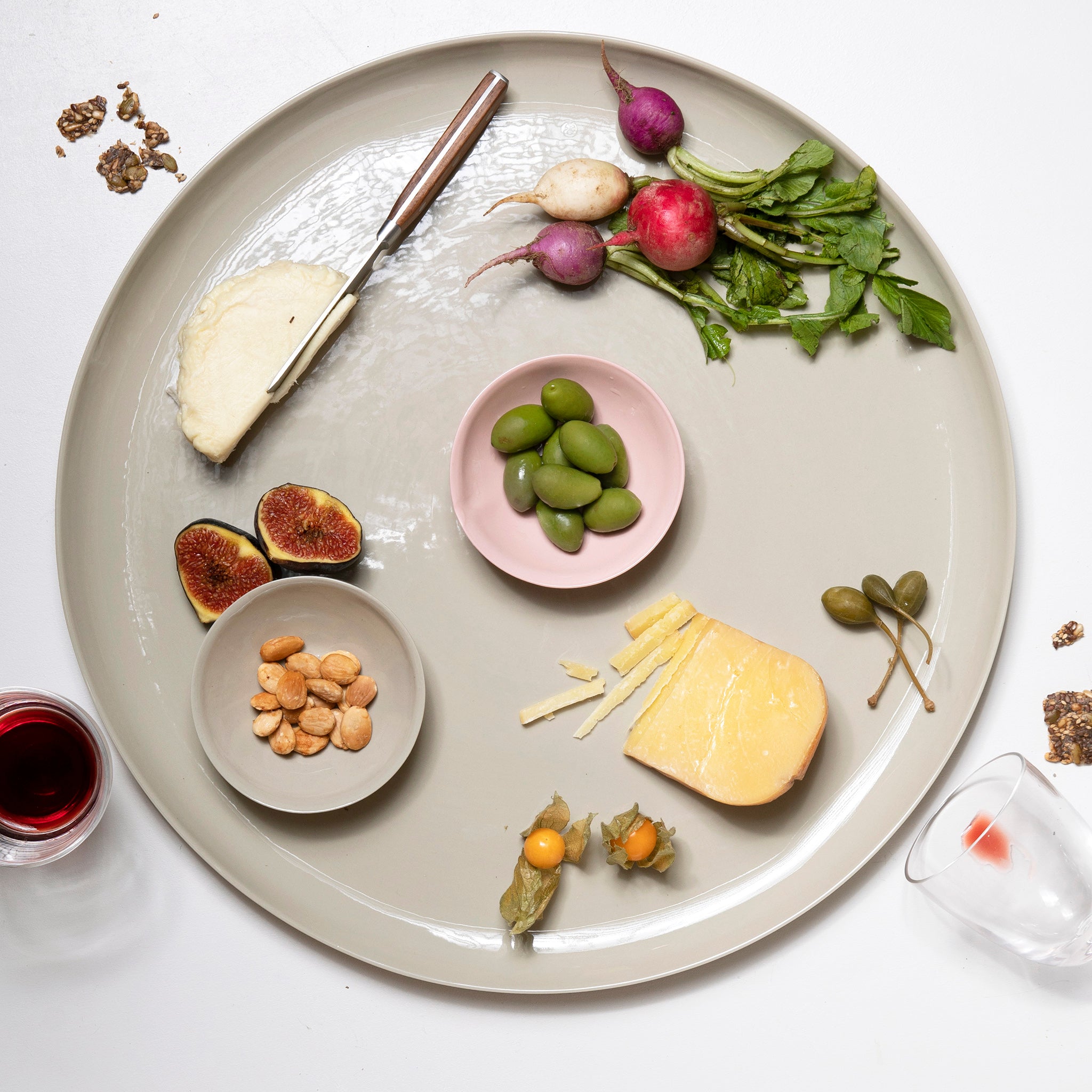 Platter with assorted cheeses, fruits, and nuts on a white background