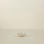 Small white ceramic bowl on a beige background