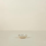 Small white ceramic bowl on a beige background