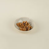 Small white bowl filled with walnuts on a beige background