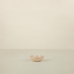 Small pink ceramic bowl on a beige background