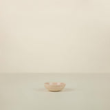 Small pink ceramic bowl on a beige background