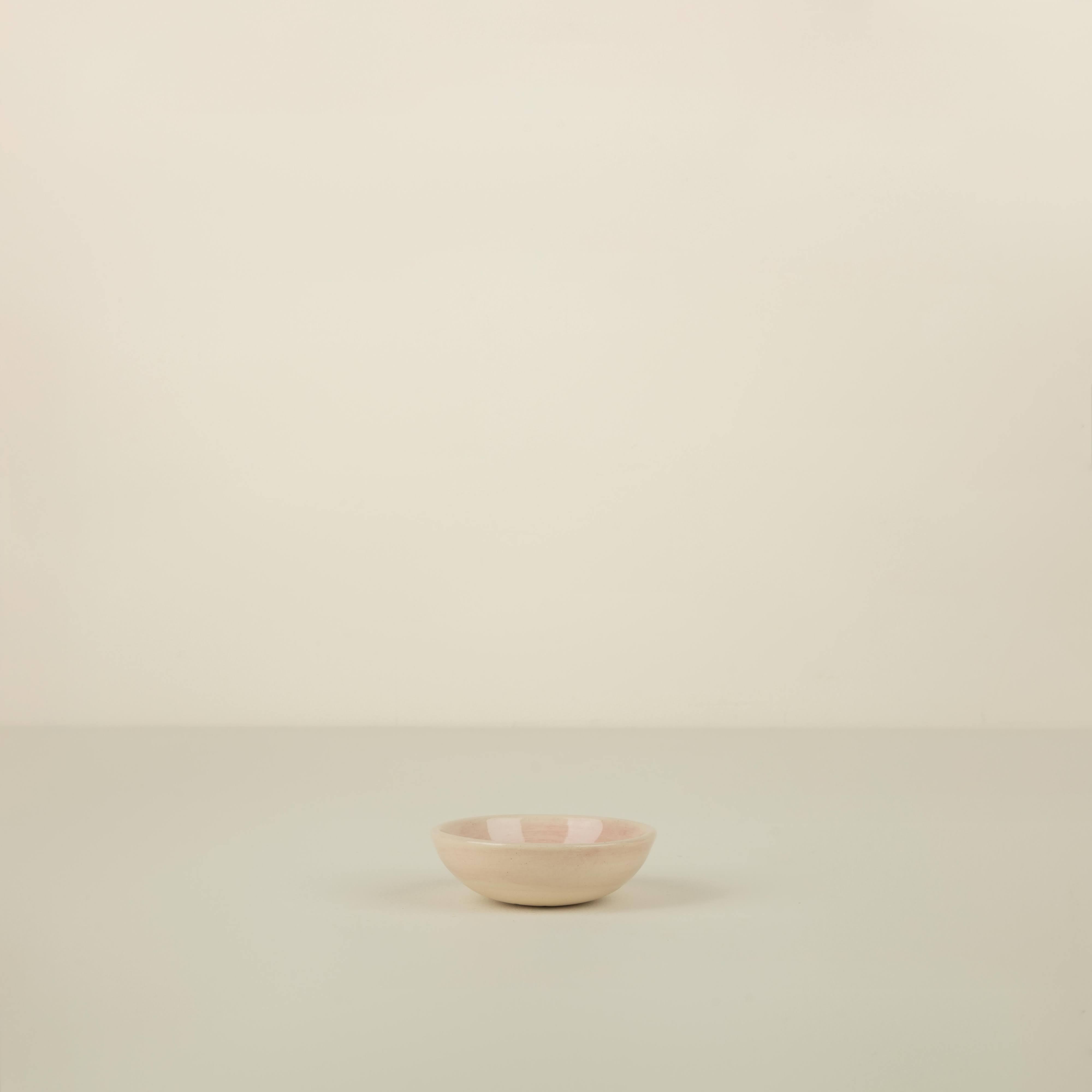 Small pink ceramic bowl on a beige background