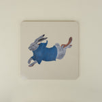 square placemat with a rabbit design wearing a blue sweater on a beige background