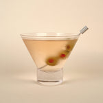 Cocktail in a martini glass with olives on a beige background