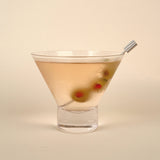 Cocktail in a martini glass with olives on a beige background