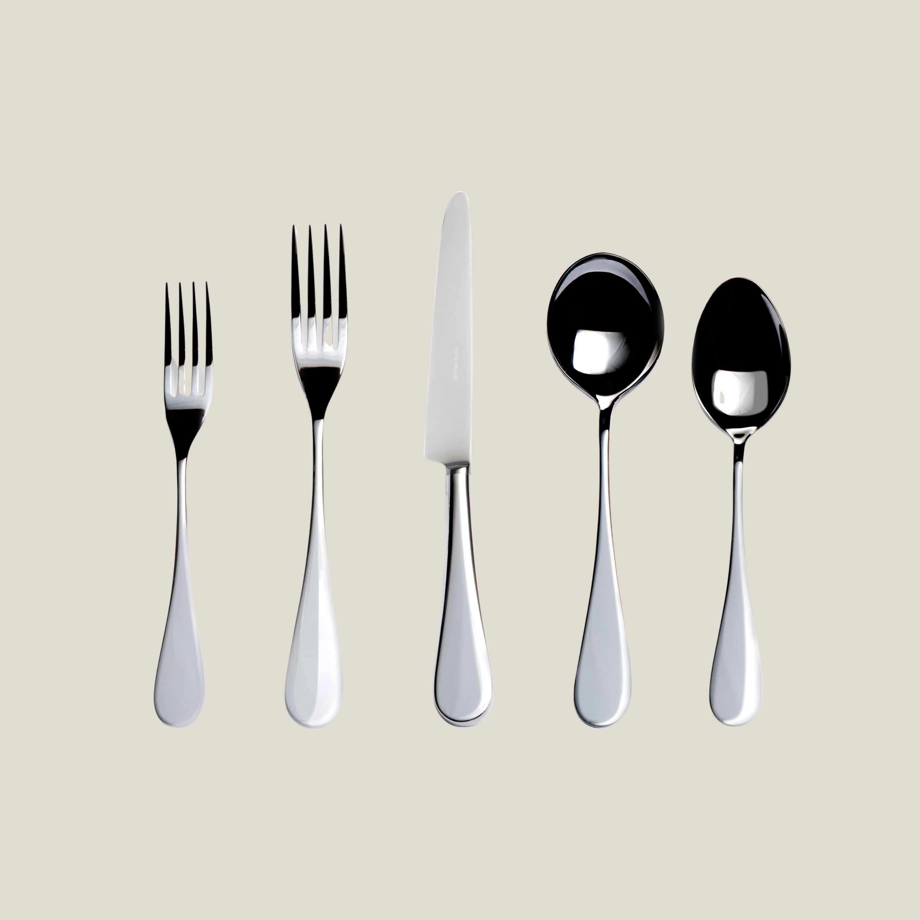 Set of silver cutlery including forks and spoons on a beige background