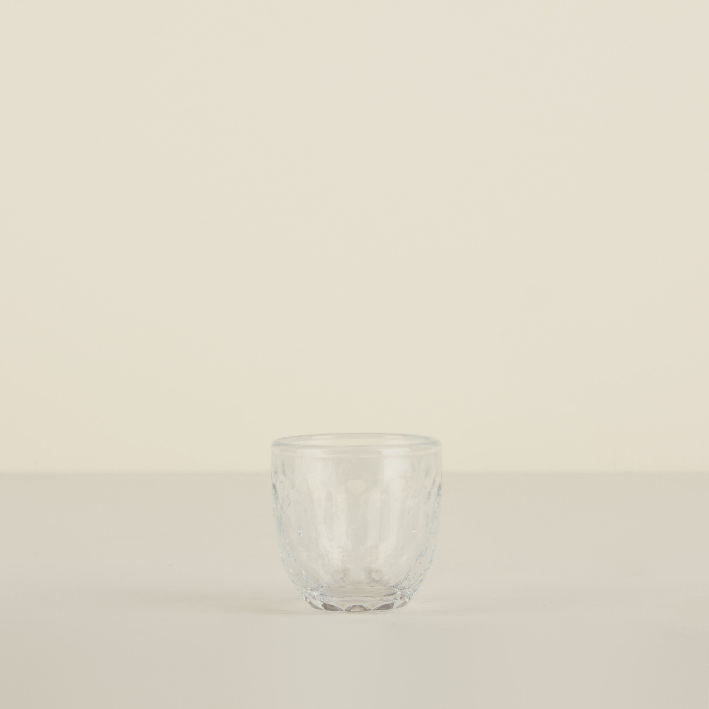 Clear glass tumbler on a beige background