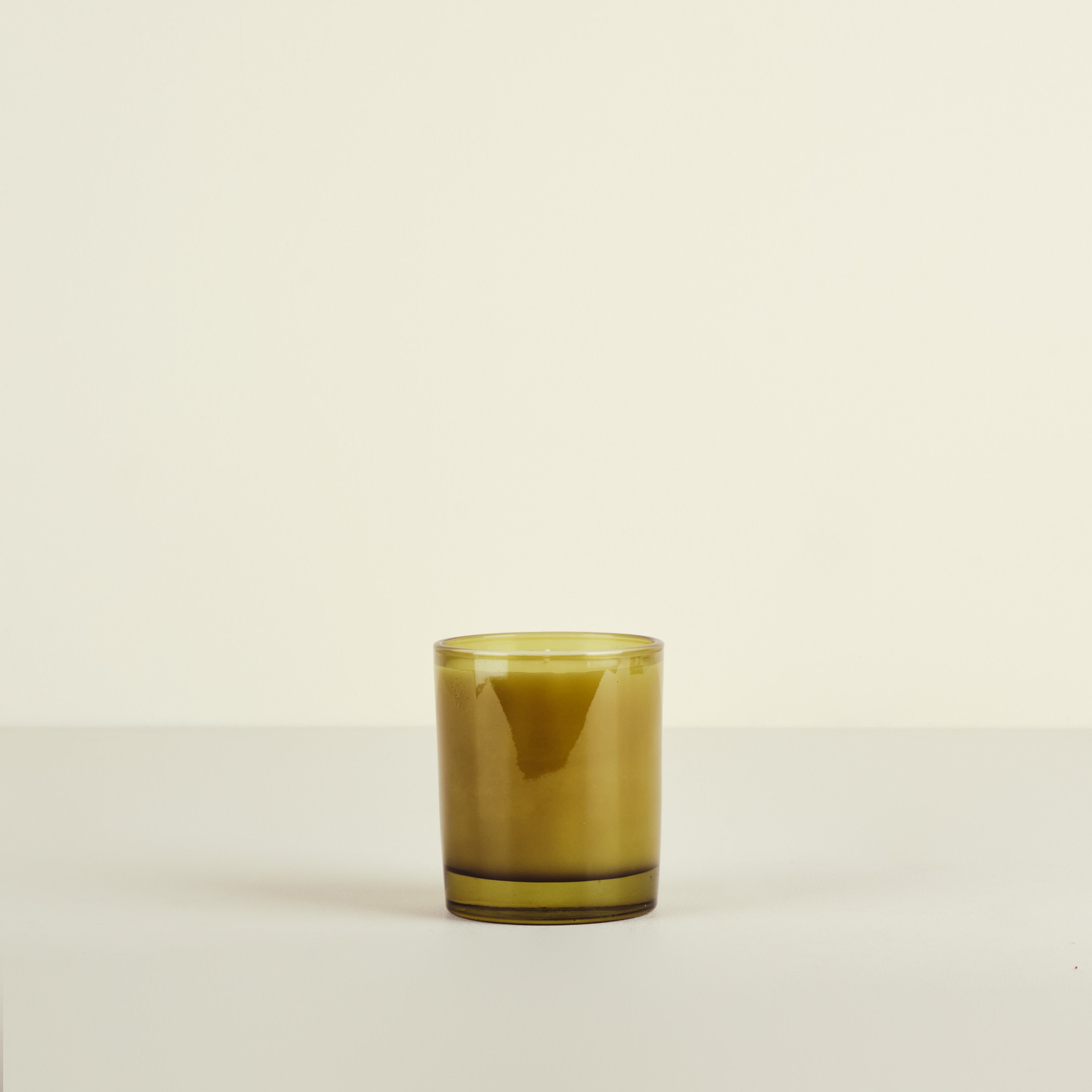 Green glass candle on a beige background