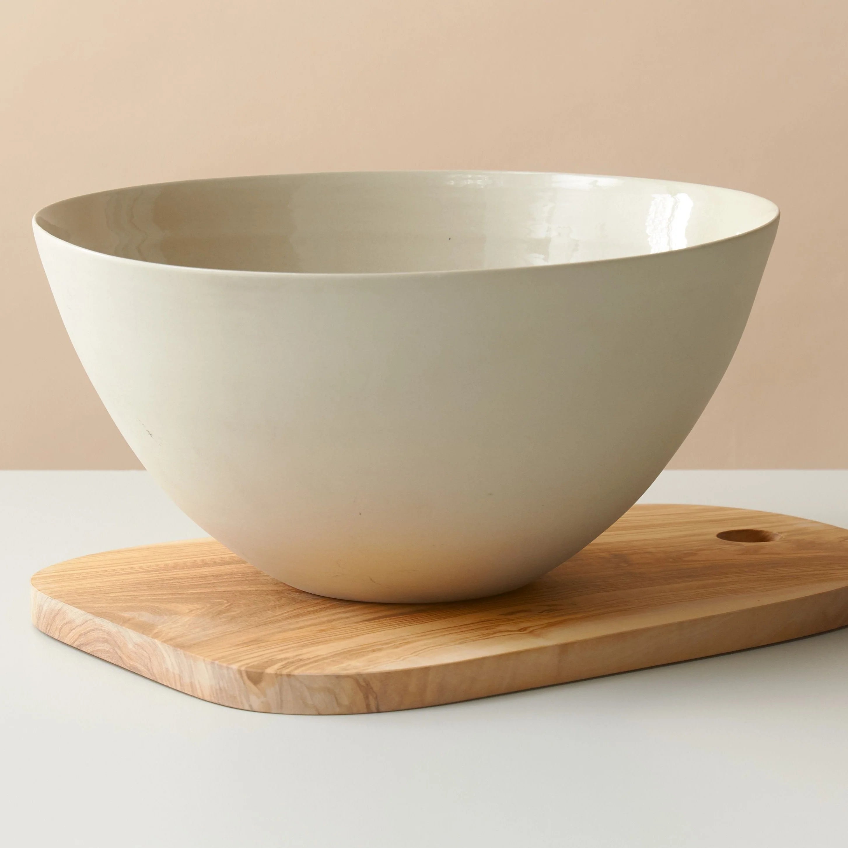 White ceramic bowl on a wooden cutting board with a beige background