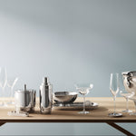 Silver tableware set on a wooden table against a gray wall