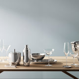Silver tableware set on a wooden table against a gray wall