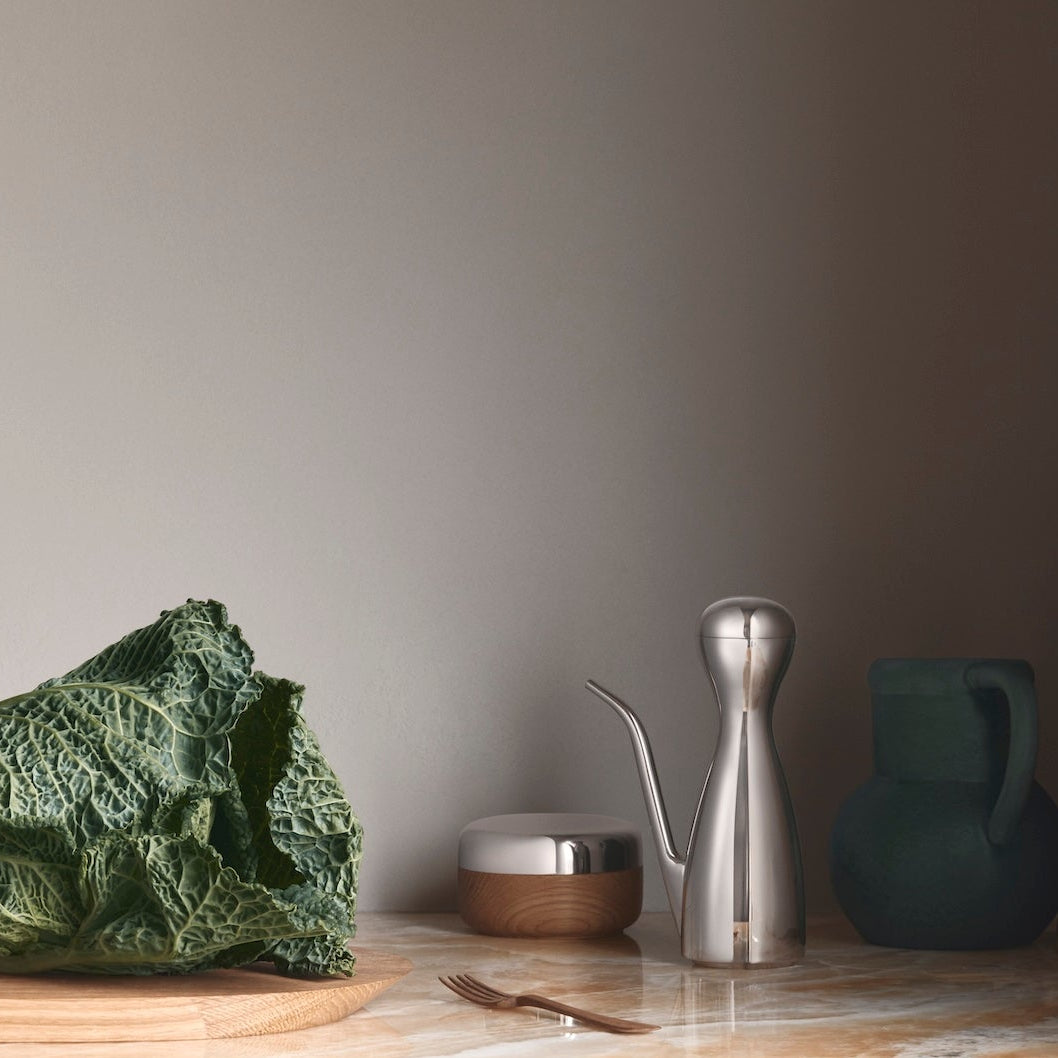 Green cabbage on a wooden cutting board with kitchen utensils in the background