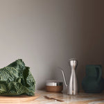 Green cabbage on a wooden cutting board with kitchen utensils in the background