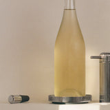 Bottle of white wine with a glass, cork, and decorative elements on a table.