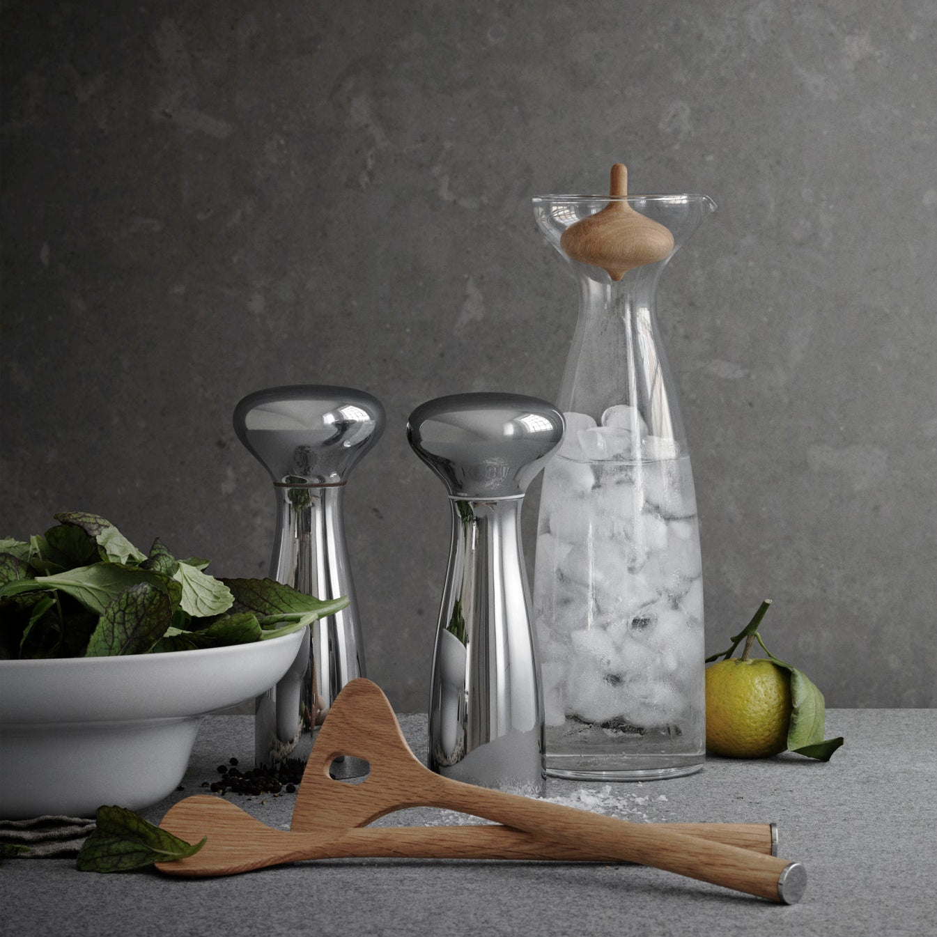 Decorative items including a glass container with ice, a wooden spatula, and a bowl of greens on a gray surface.