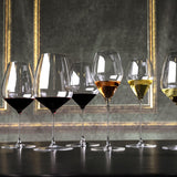 Row of wine glasses with different types of wine on a dark surface with decorative background
