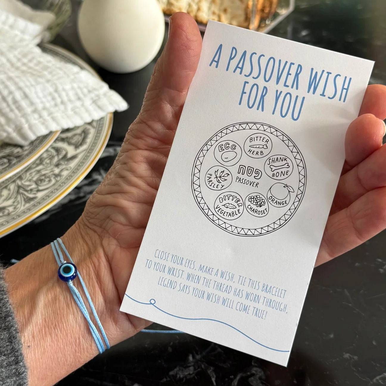 Hand holding a Passover wish card with a decorative background