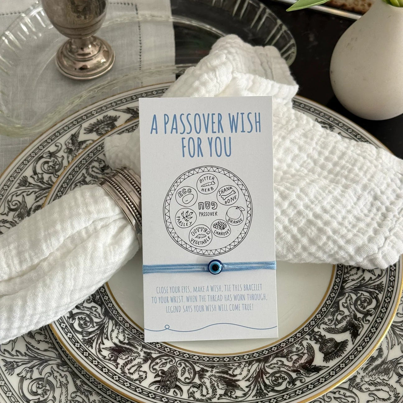 Passover wish card on a decorative plate with silver goblet and flowers.