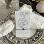 Passover wish card on a decorative plate with silver goblet and flowers.