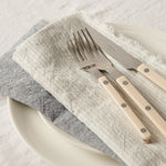 Set of cutlery with beige handles on a white plate with gray napkin