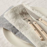 Set of cutlery with beige handles on a white plate with gray napkin