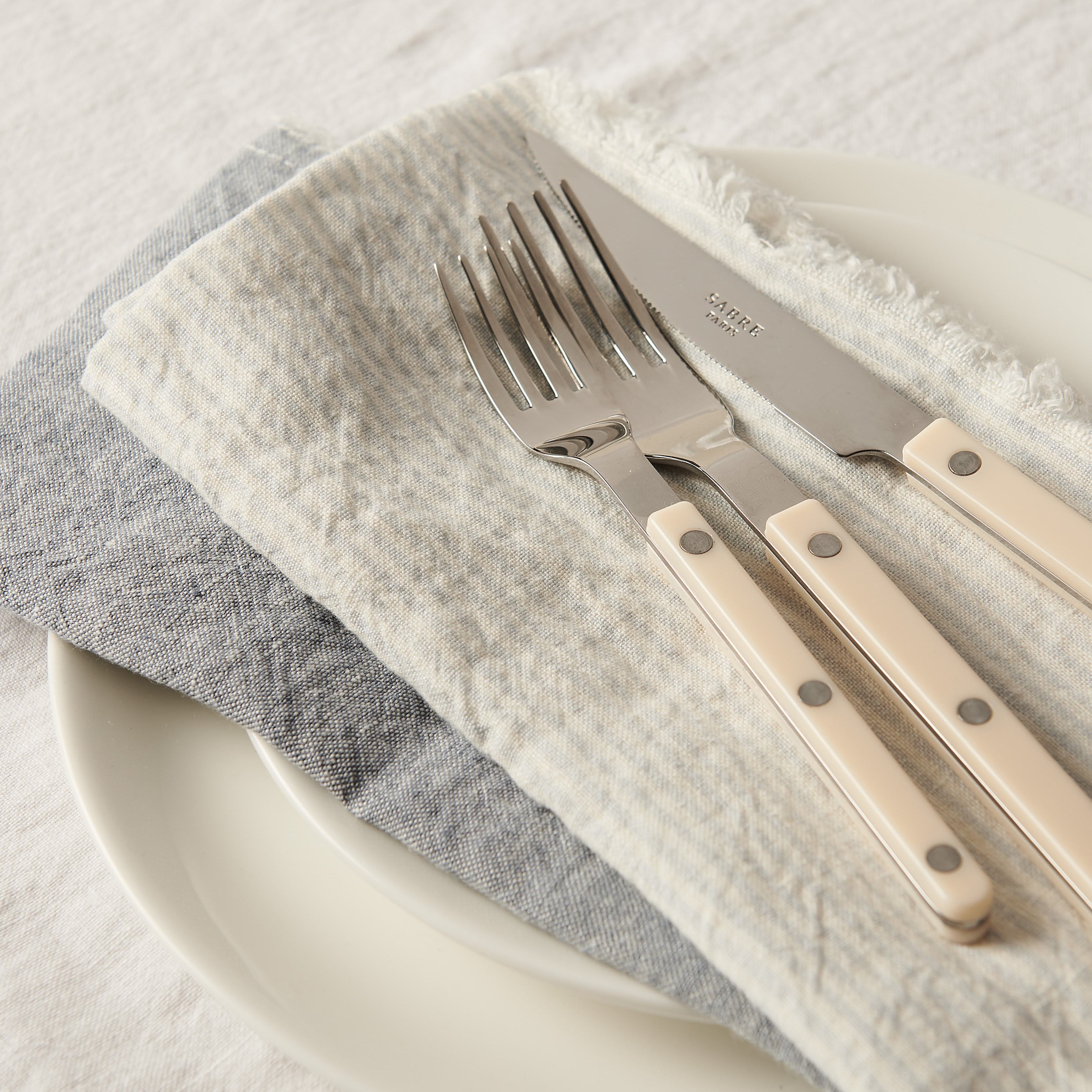 Set of cutlery with beige handles on a white plate with gray napkin