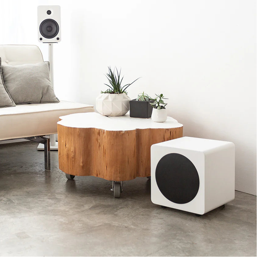 Modern living room with a sofa, coffee table, and speakers.