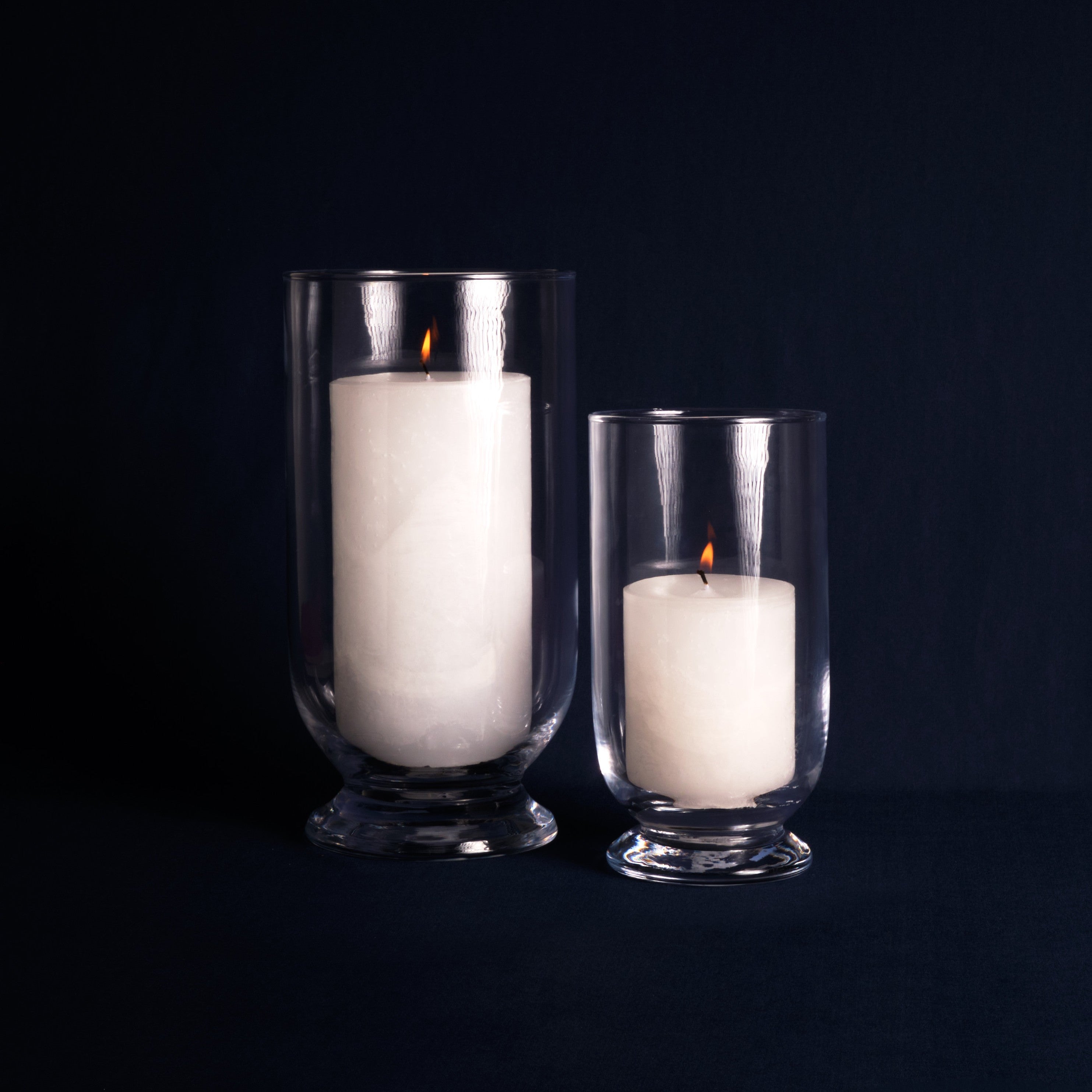 Two white candles in glass holders on a black background