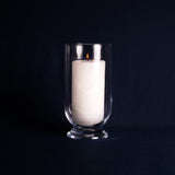 White candle in a clear glass holder on a black background