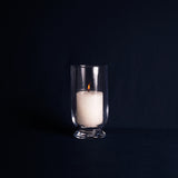 White candle in a clear glass holder on a black background
