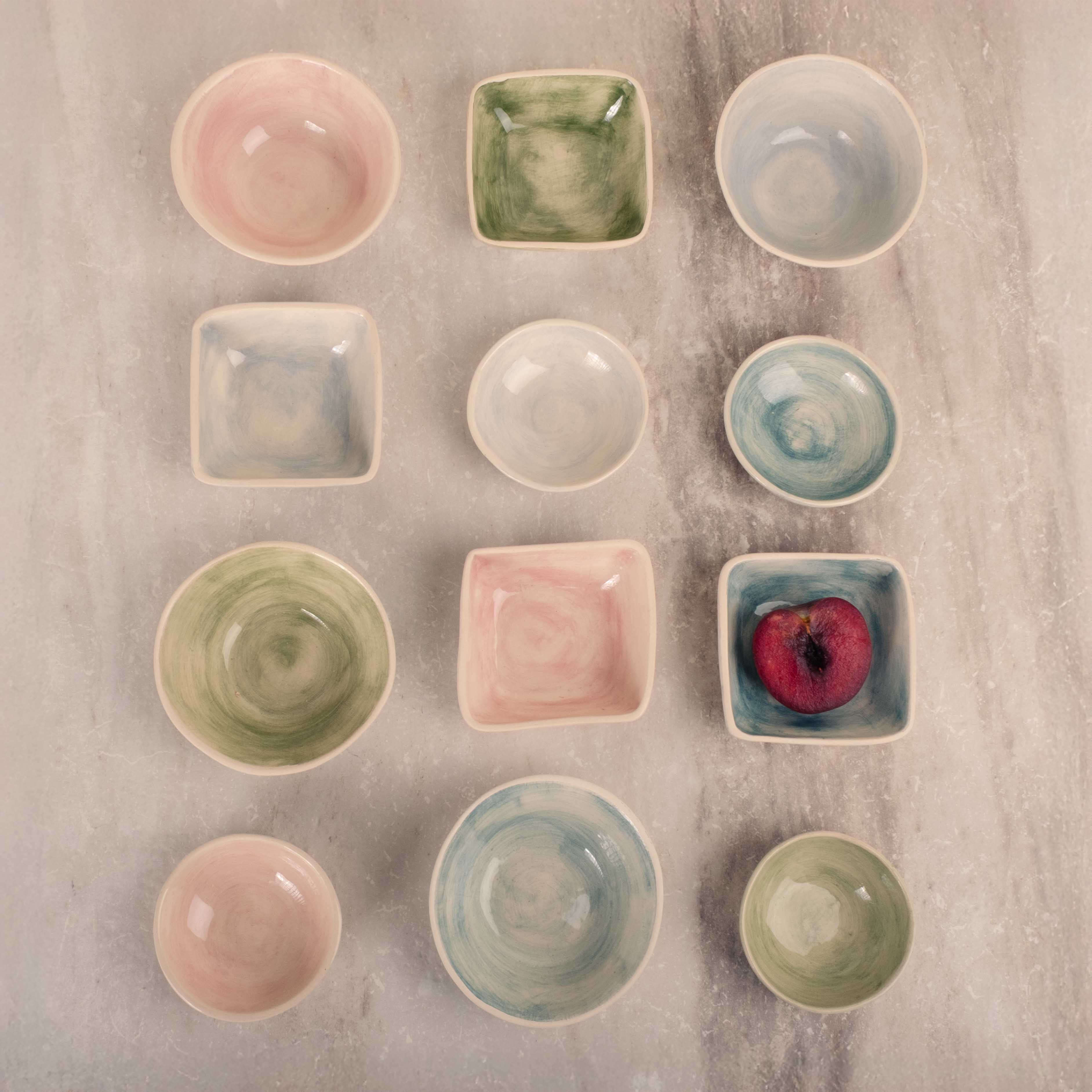 Collection of ceramic bowls and plates in various colors on a textured surface