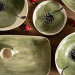 Green ceramic dishes with floral designs on a wooden surface.