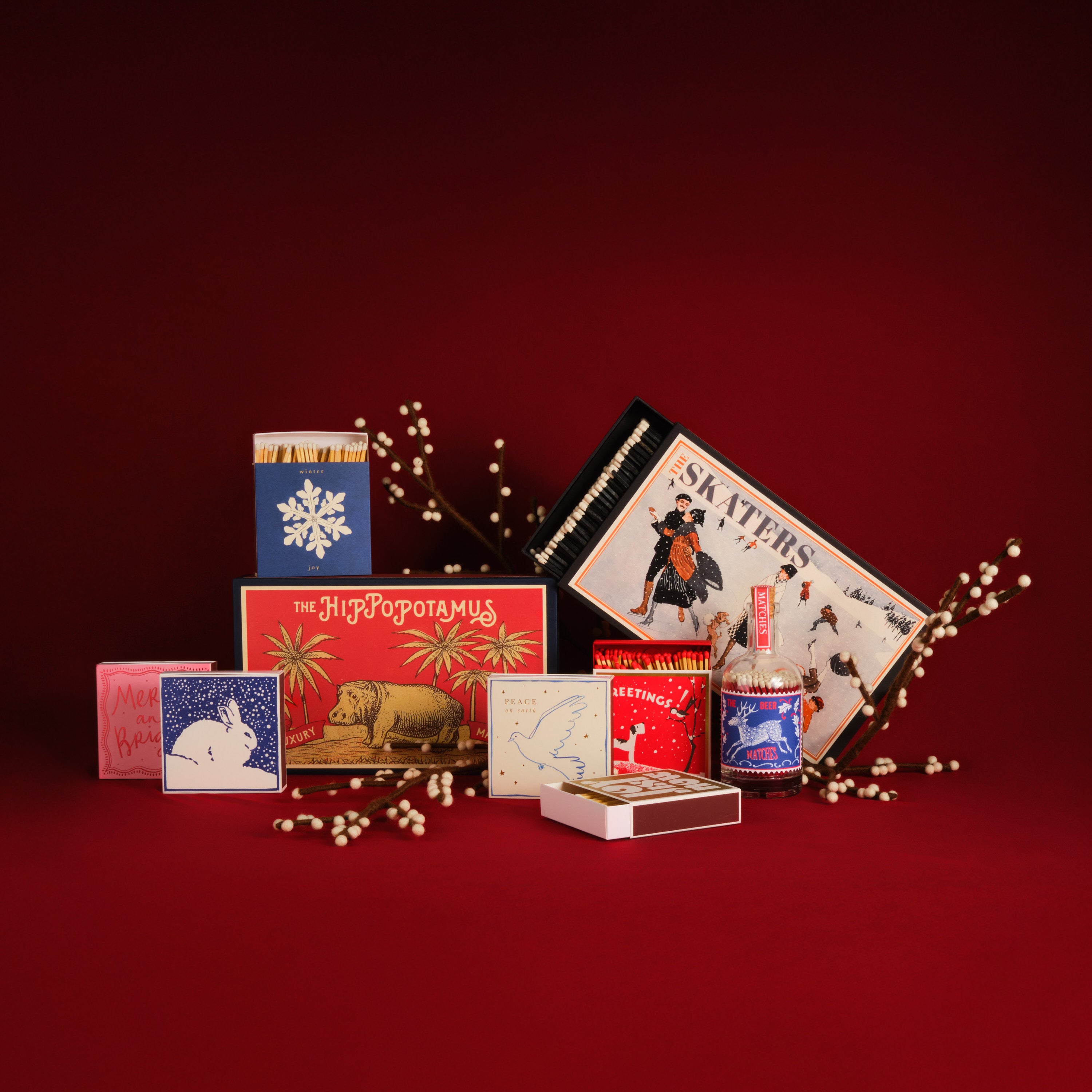 Collection of vintage-style matchboxes and a bottle on a red background