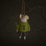 Small plush mouse toy wearing a green coat hanging on a branch against a dark background