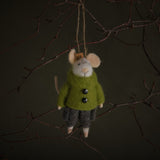 Small plush mouse toy wearing a green coat hanging on a branch against a dark background