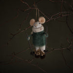 Felted mouse ornament in a green sweater hanging from a branch against a dark background