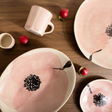 Pink ceramic plates with black floral designs on a wooden table.