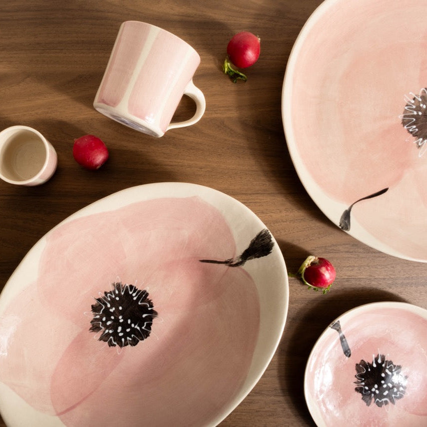 Pink ceramic plates with black floral designs on a wooden table.