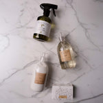 Four cleaning product bottles and a soap box on a marble surface