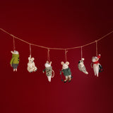 Set of small animal figurines in winter clothing hanging on a string against a red background