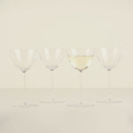 Four wine glasses with white wine on a beige background