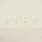 Four wine glasses with white wine on a beige background