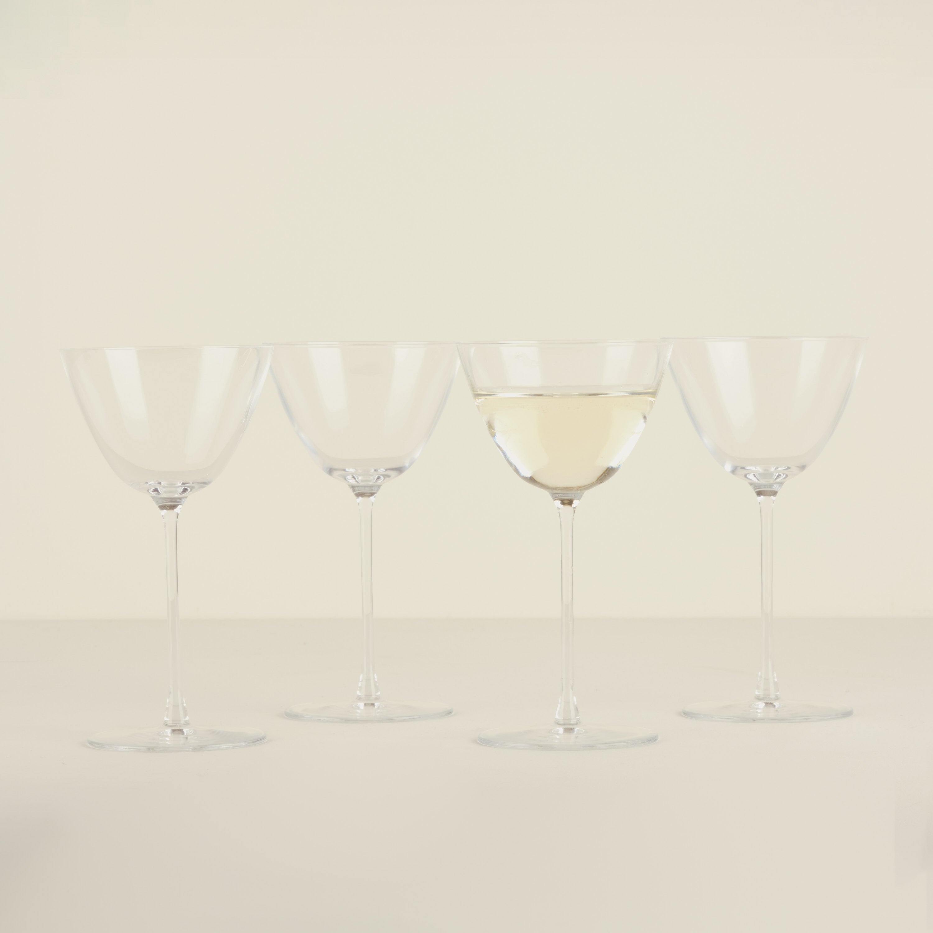 Four wine glasses with white wine on a beige background