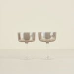 Two smoked glass goblets on a beige background