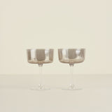 Two smoked glass goblets on a beige background