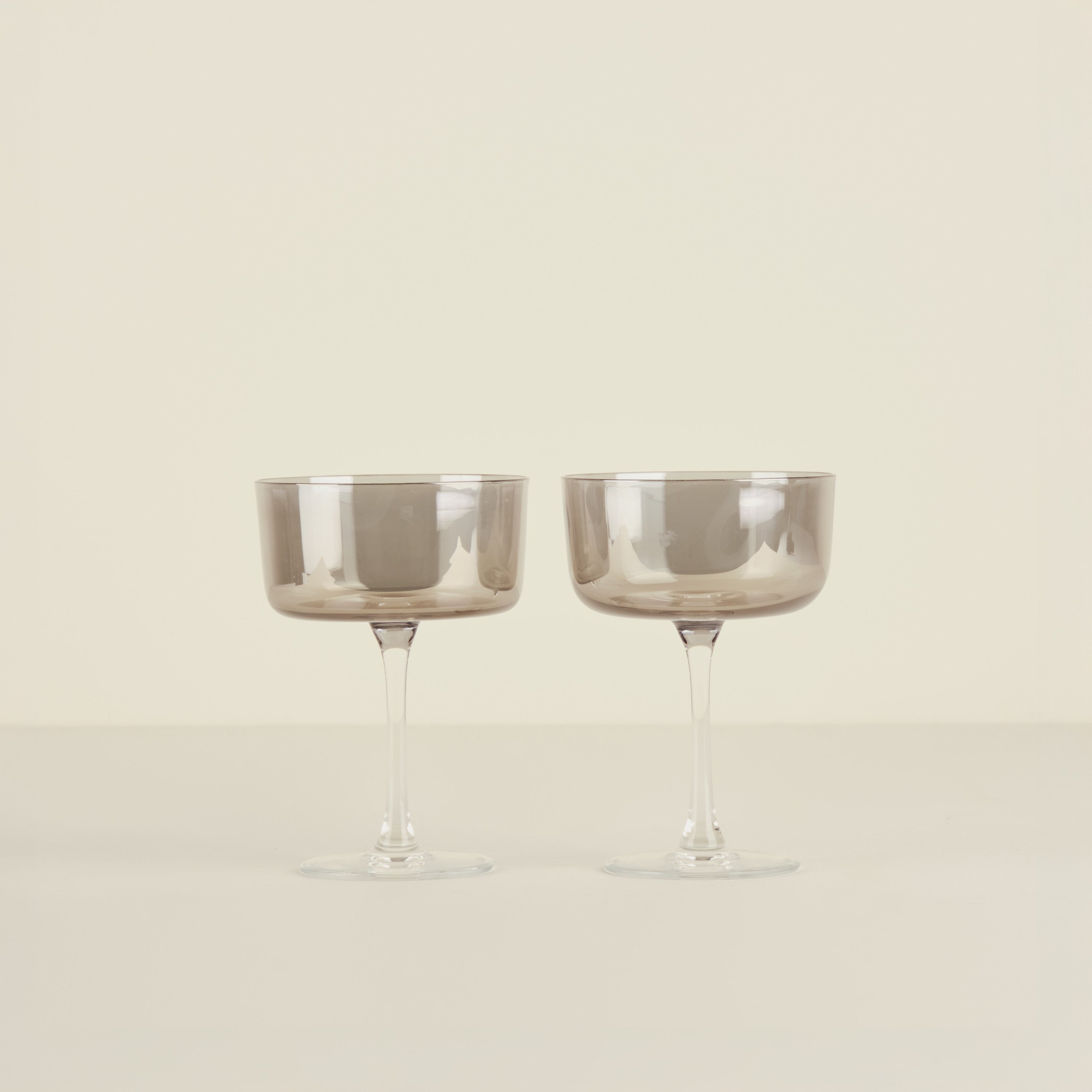 Two smoked glass goblets on a beige background