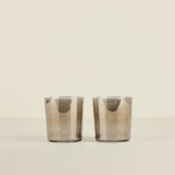 Two smoked glass tumblers on a beige background