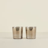 Two smoked glass tumblers on a beige background